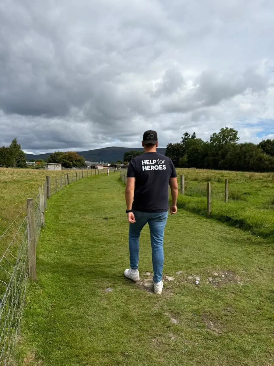 Roger walking through a field in the Scottish Highlands in a Help for Heroes shirt